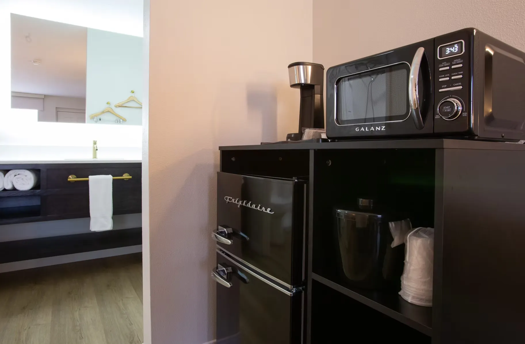Mini fridge topped with a microwave and coffee maker in the room's kitchenette nook.