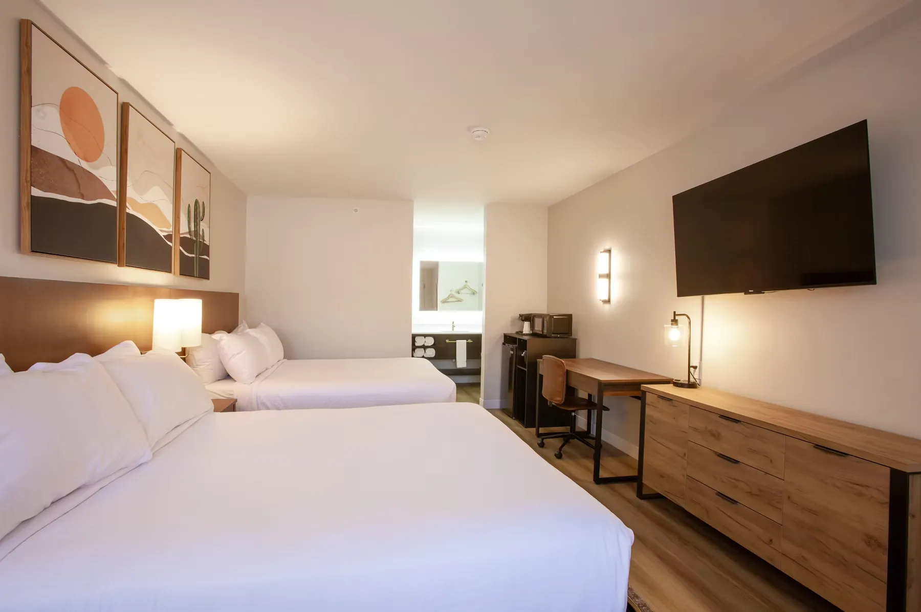 Side view of the queen beds alongside a wood dresser and wall-mounted TV.