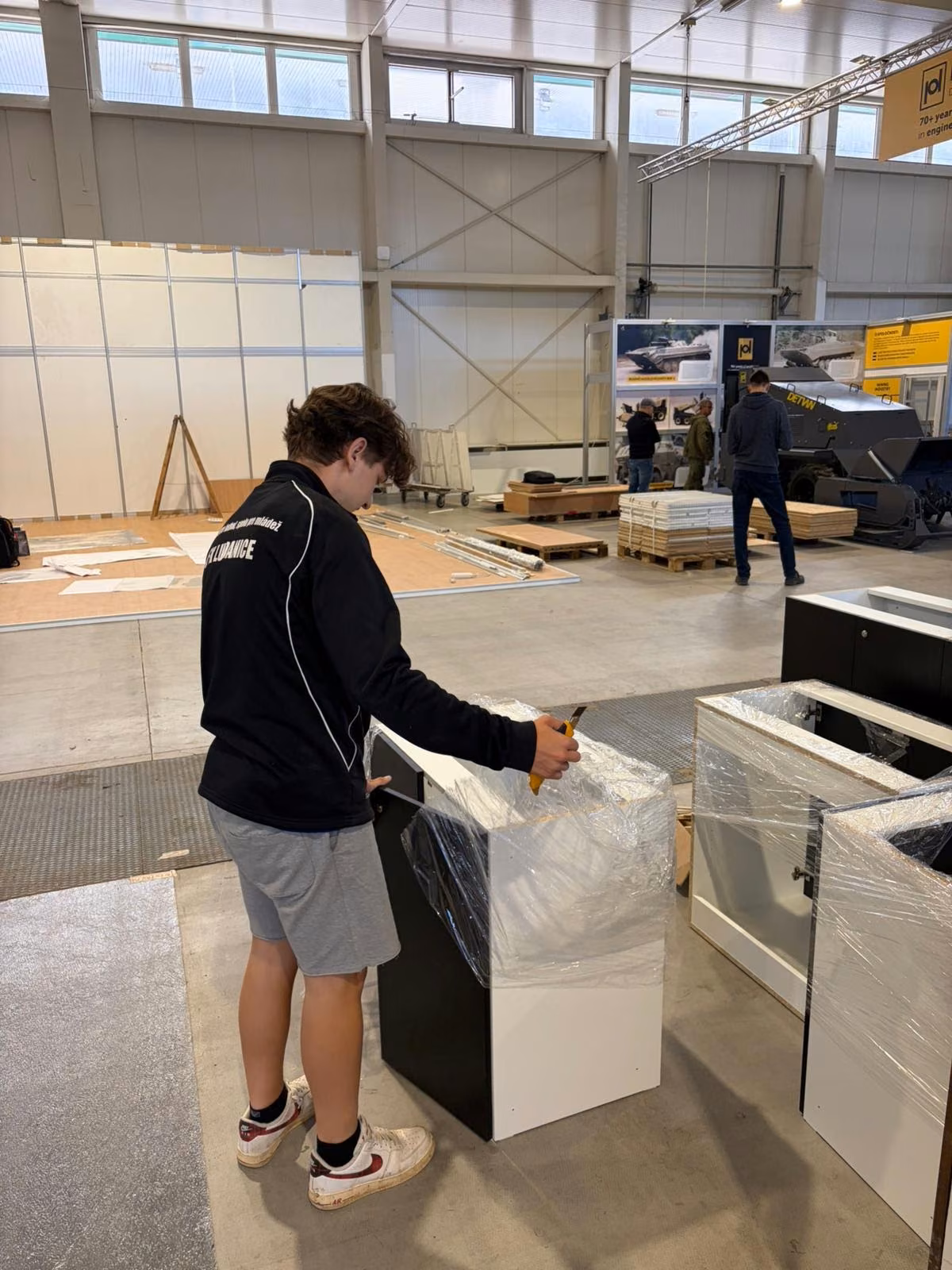 Temp worker wrapping goods in stretch film in a warehouse