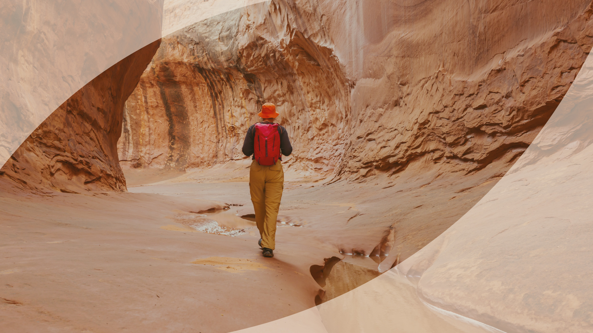 Hiker walking a trail through a sandstone canyon