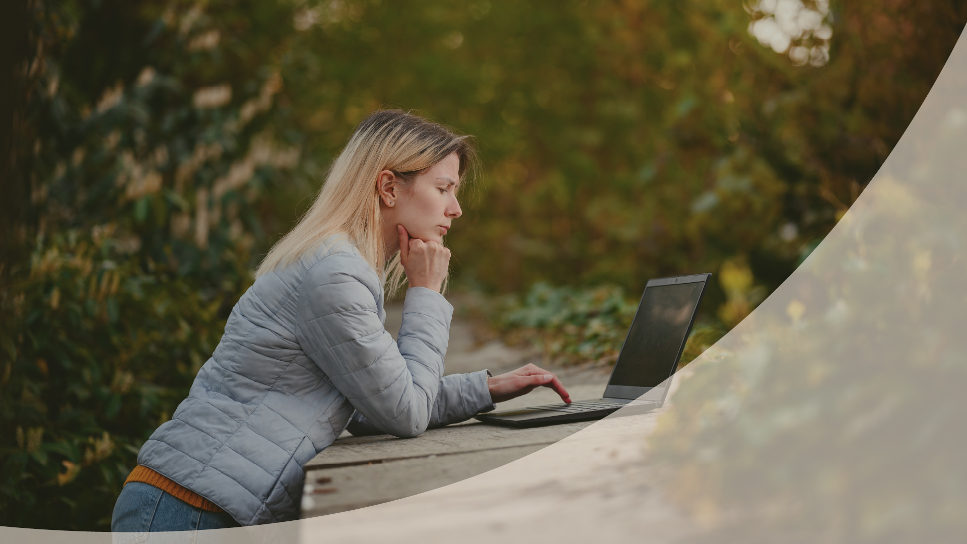 Woman thinking at a laptop at an outdoor table