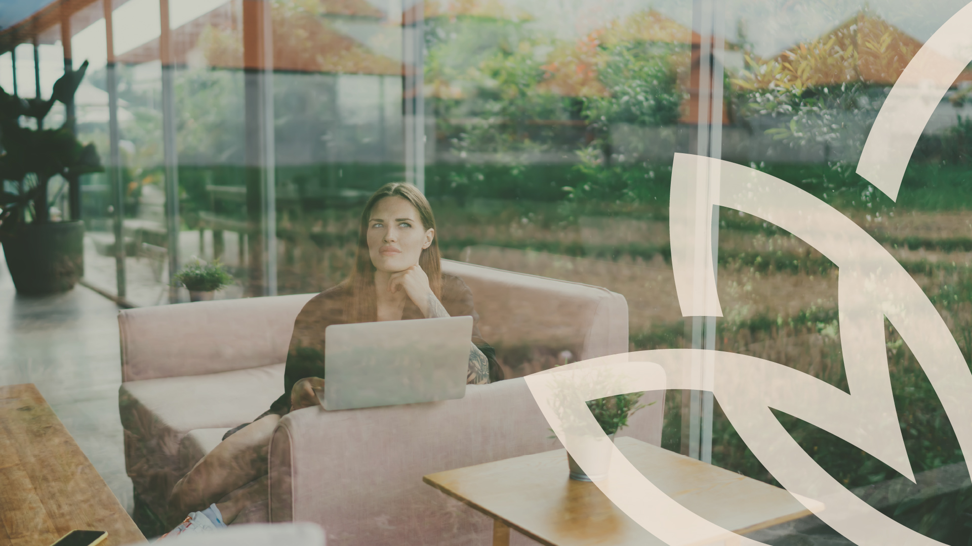 Woman on a sofa with a laptop by a window overlooking trees