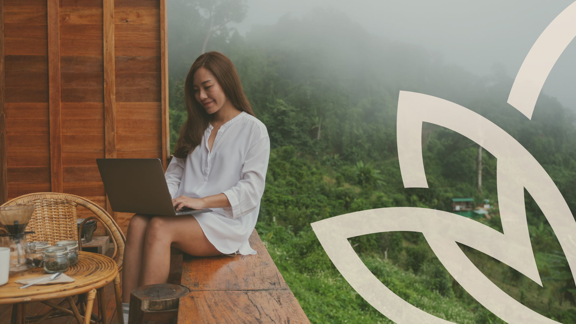 Woman with a laptop sitting outdoors in misty hills