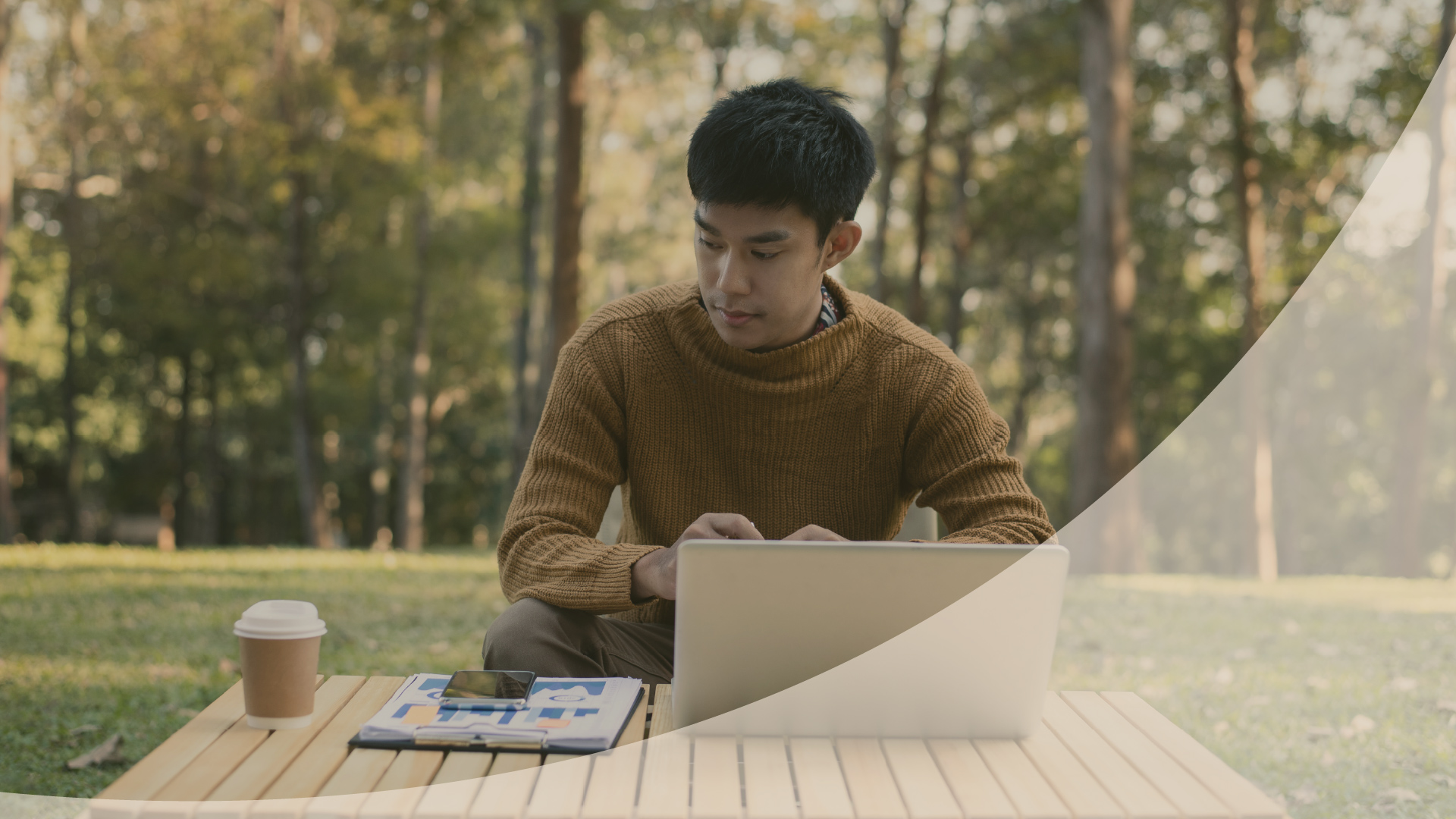Man using a laptop at a picnic table in the woods