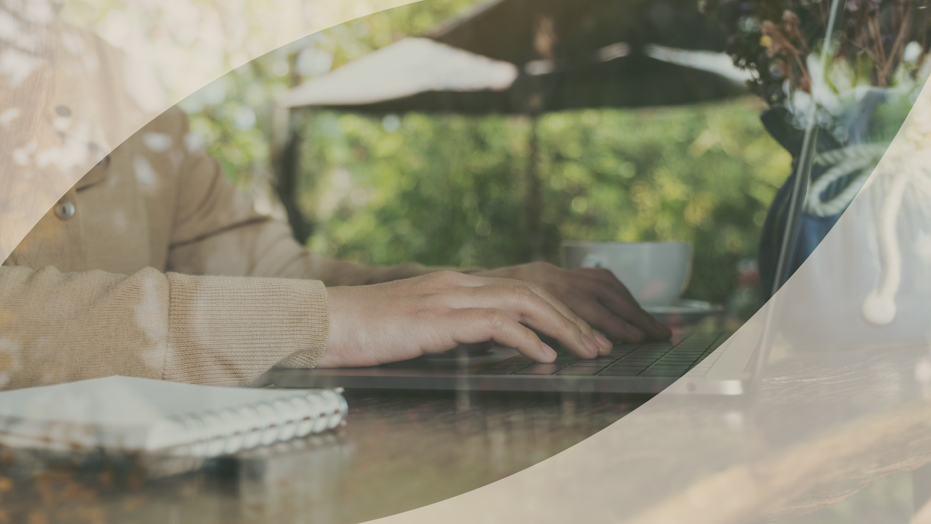 Hands typing on a laptop at an outdoor table