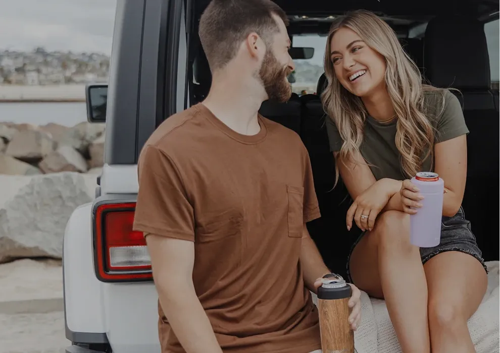 Couple sitting in the back of a Jeep holding Frost Buddy tumblers