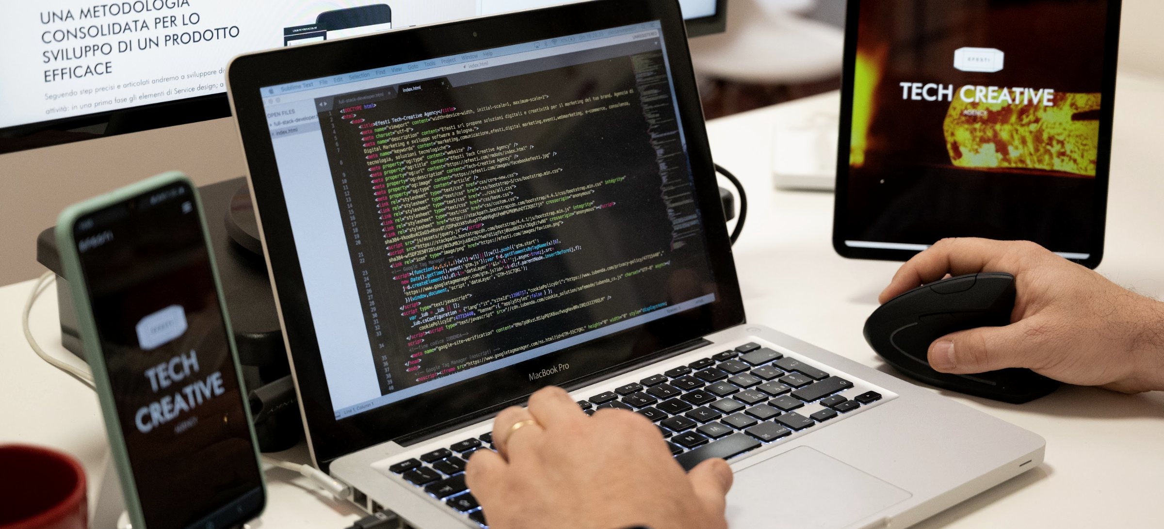 Full-Stack-Entwickler von Efesti bei der Arbeit am Code, mit Smartphone und Tablet für Tests auf mehreren Geräten