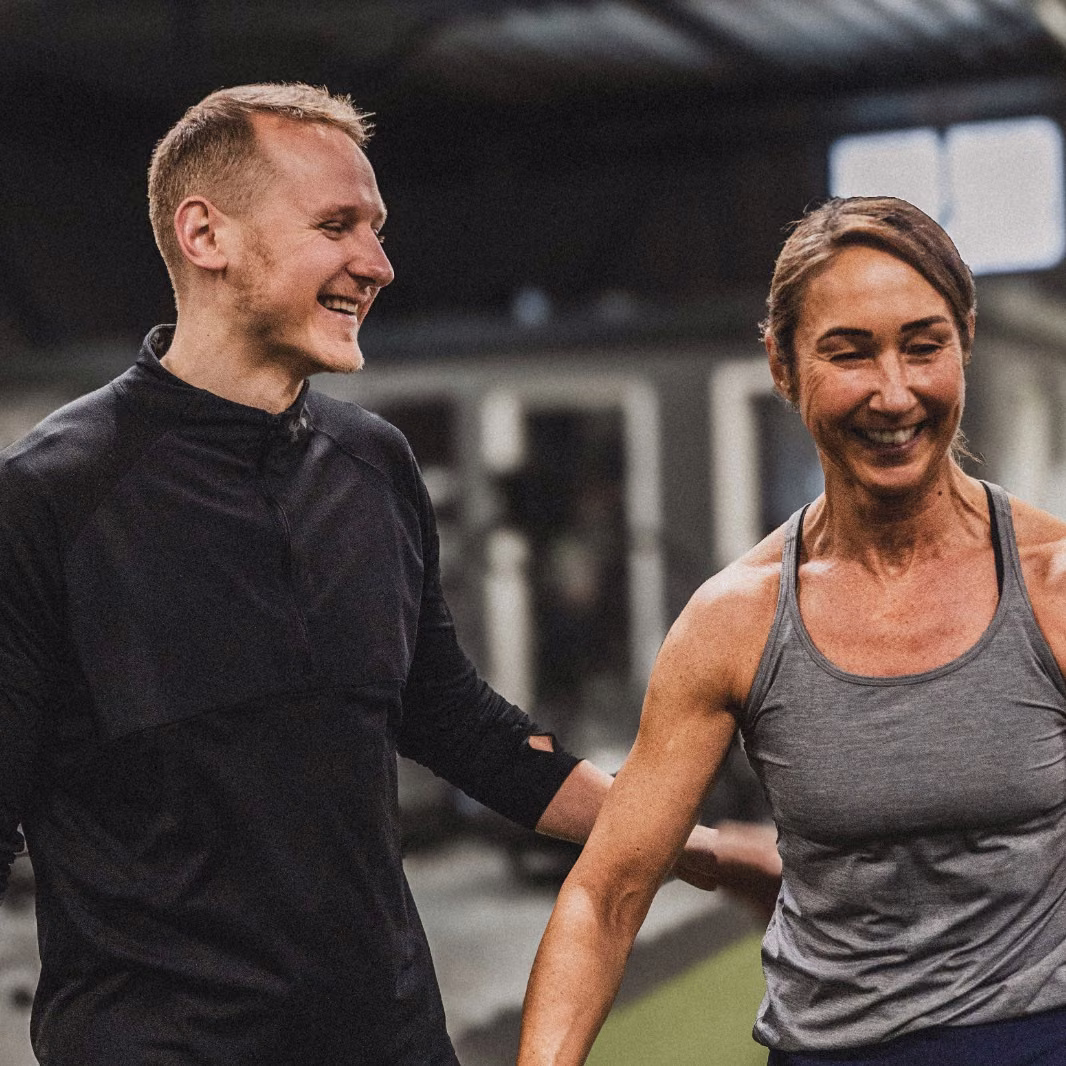 Coach und Mitglied lachen gemeinsam beim Training im ATMO Club