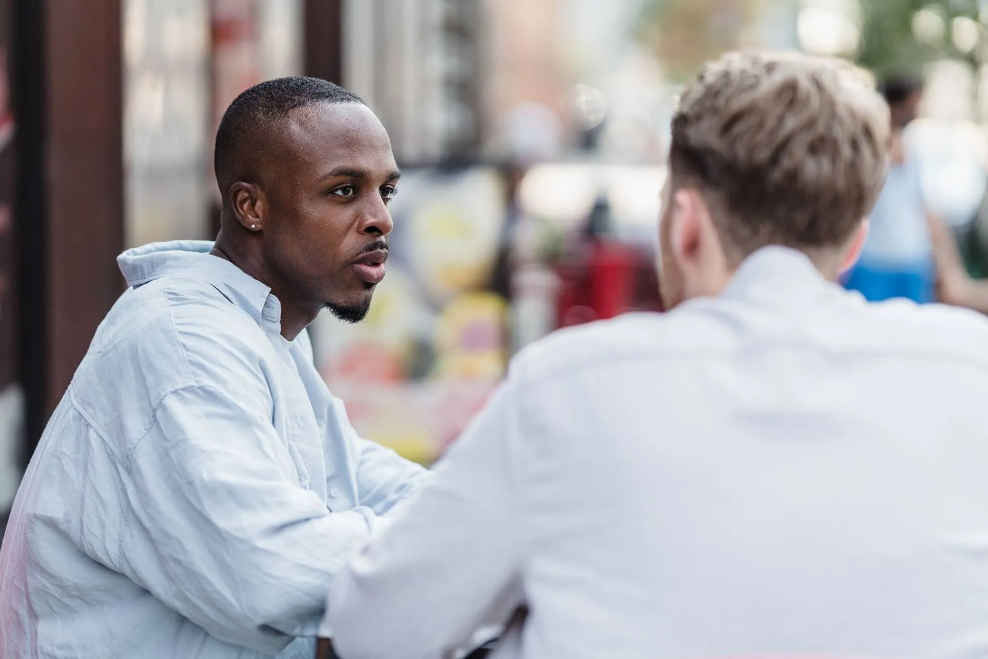 Two colleagues talking at an outdoor table on a city street