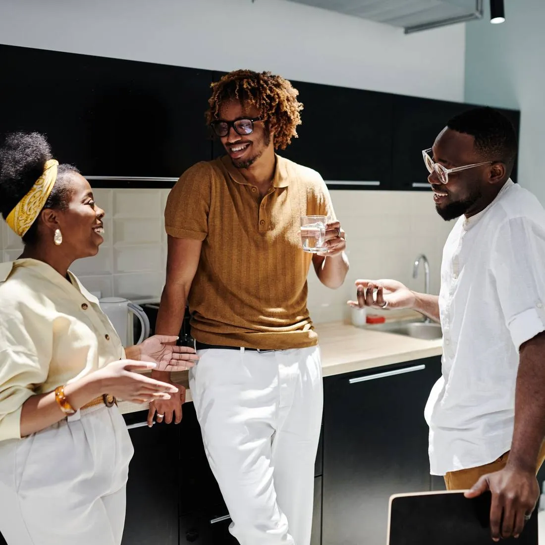 Three colleagues talking over coffee at an office kitchen counter