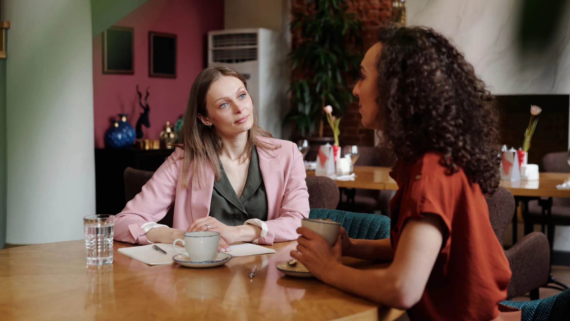 Two colleagues in conversation over coffee at a cafe table