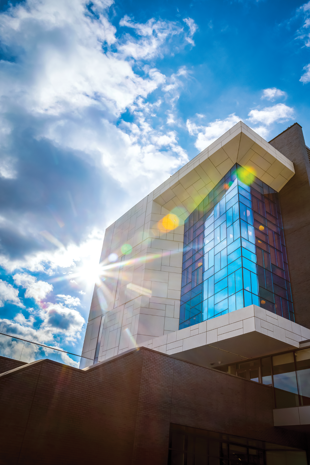 The E. A. Fernandez Idea Factory building, sunlight flaring off its tiled facade and colored-glass window wall