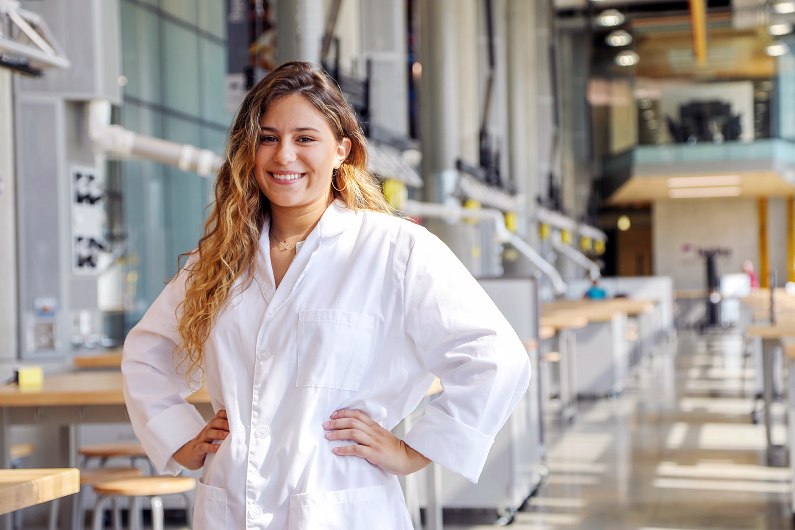 Student in a white lab coat in an engineering building