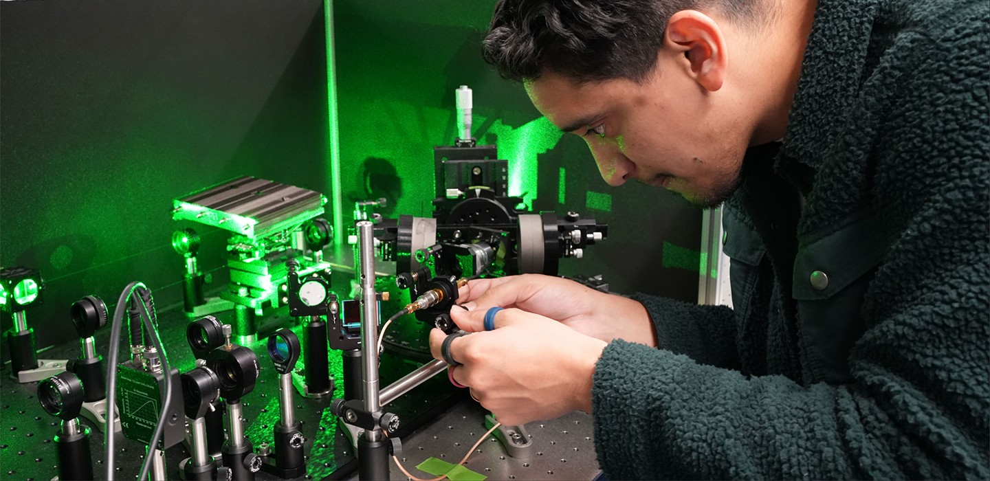 A researcher working with green laser optics equipment in a basement quantum technology lab