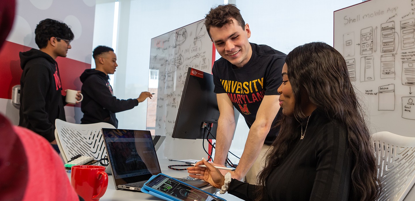 Students collaborating at a whiteboard and desk in the Startup Shell co-working space