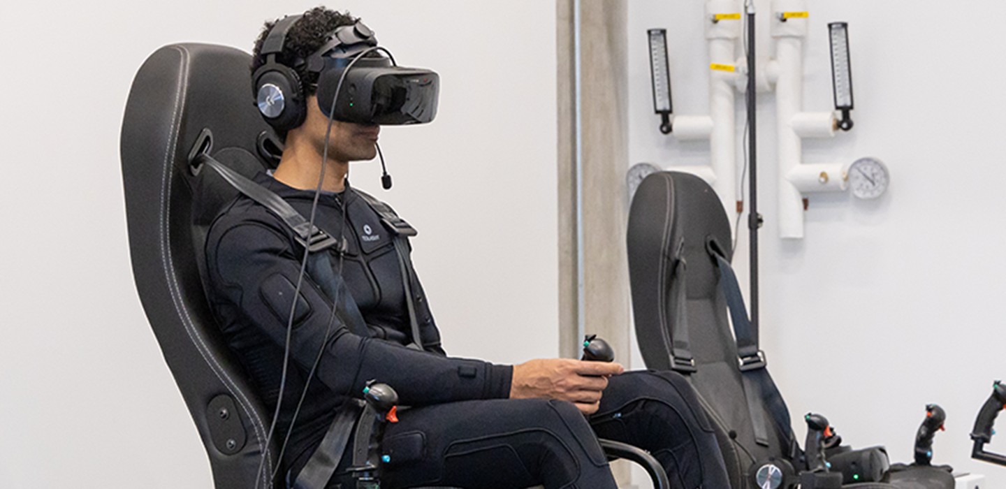 A researcher in a VR headset seated in a flight-simulator rig in the rotorcraft lab