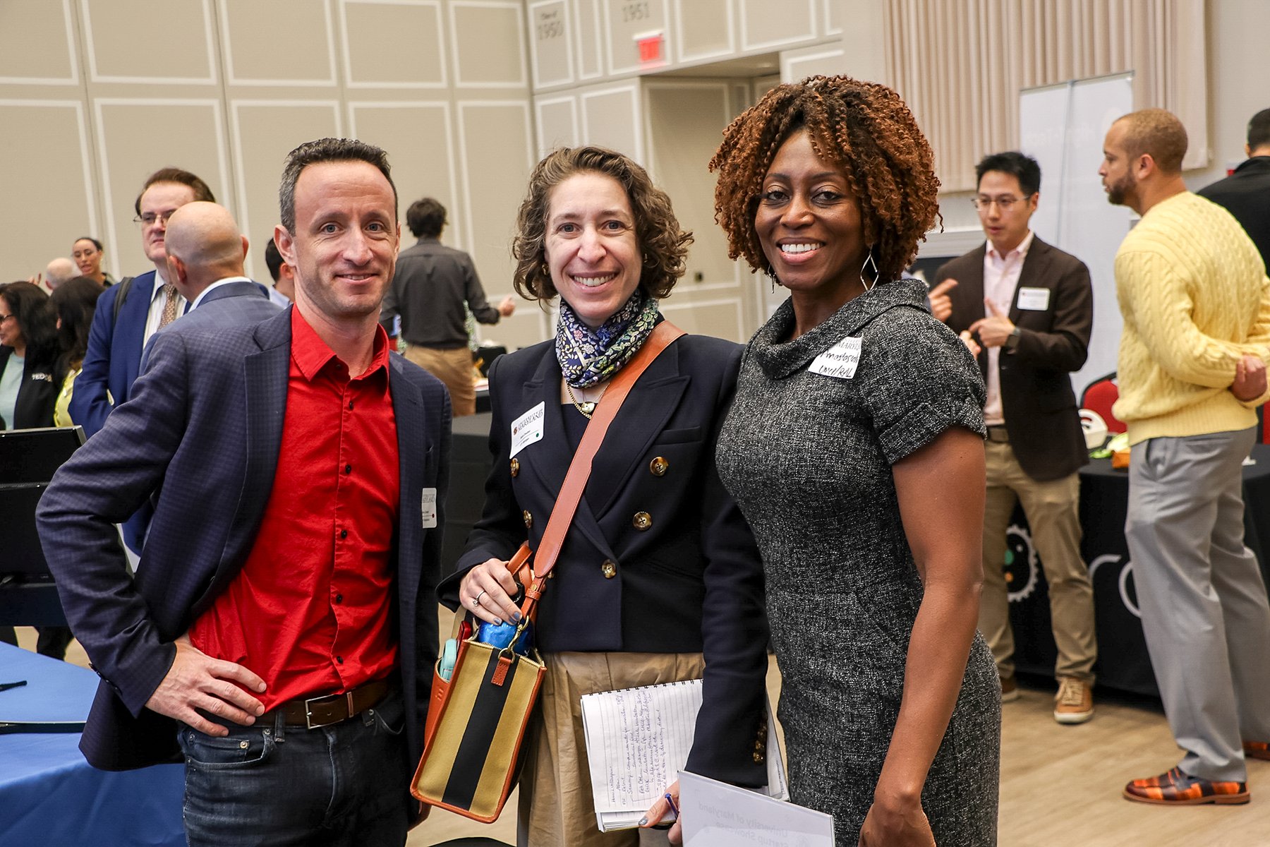 Three professionals talking and smiling at a networking event