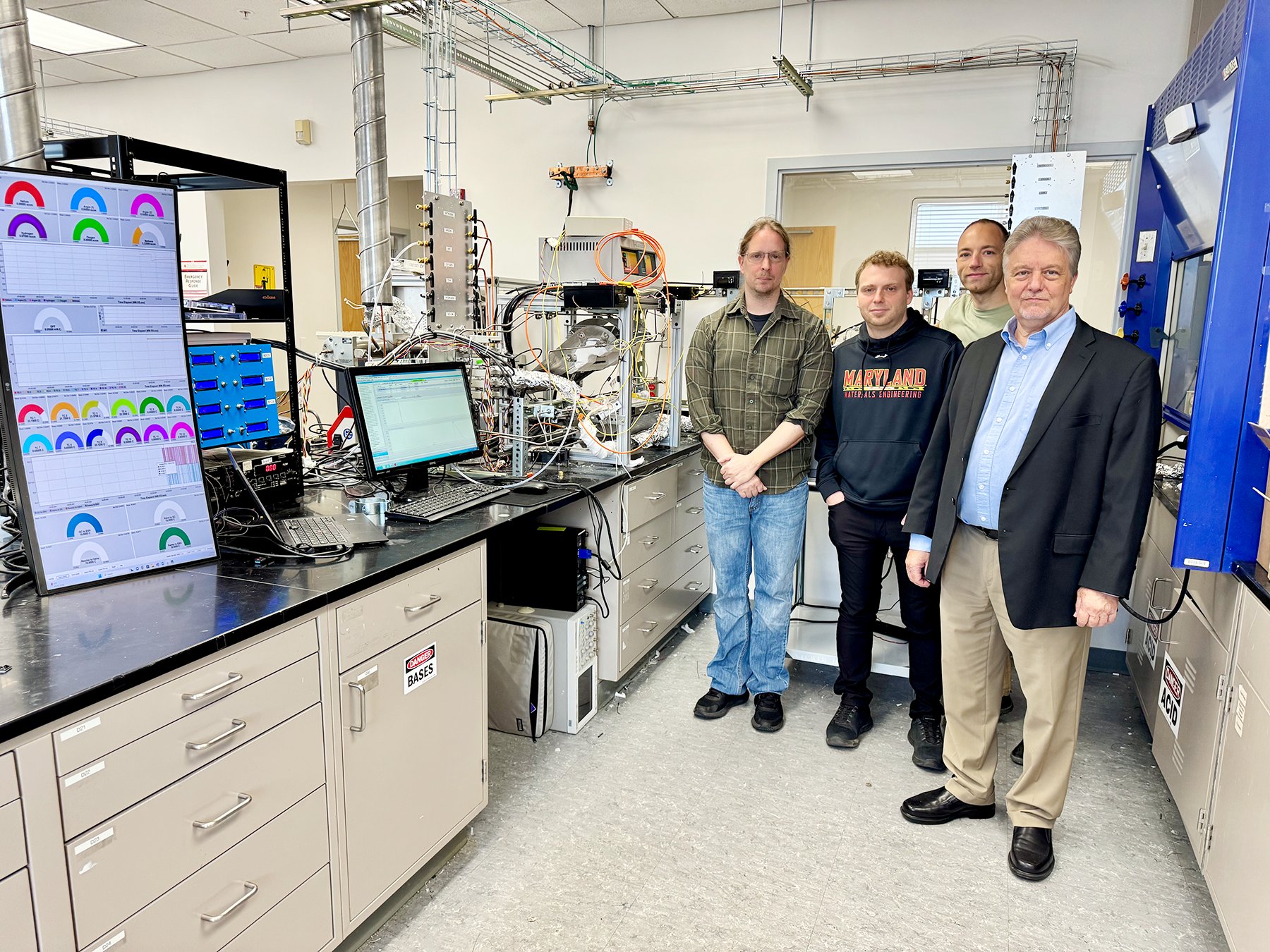 Four people standing together in a university lab surrounded by research equipment