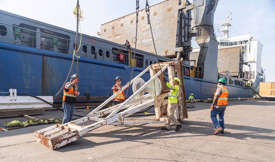 Dockside crew handling equipment beside a cargo ship