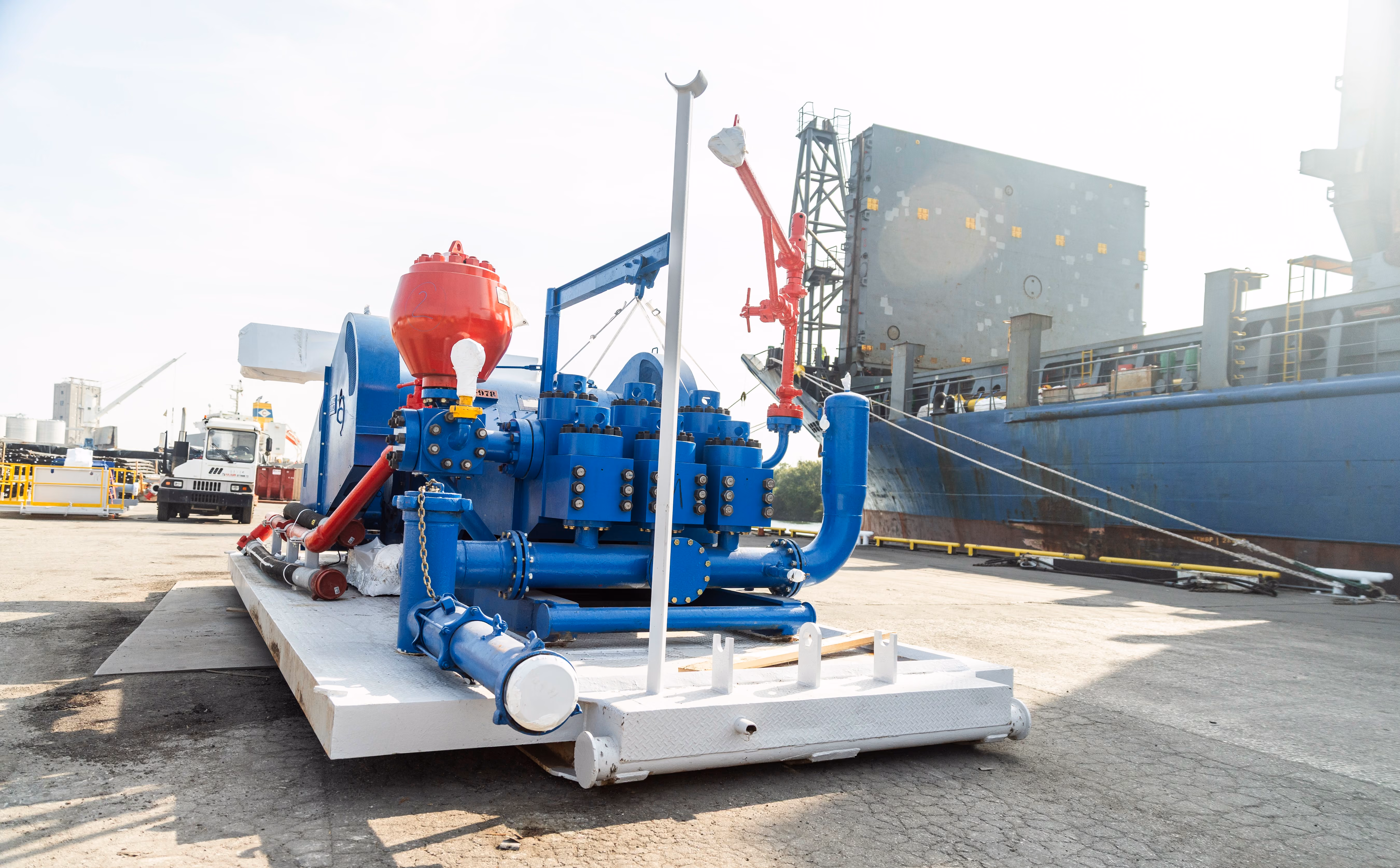 Blue industrial pump unit on a skid at a port beside a cargo ship