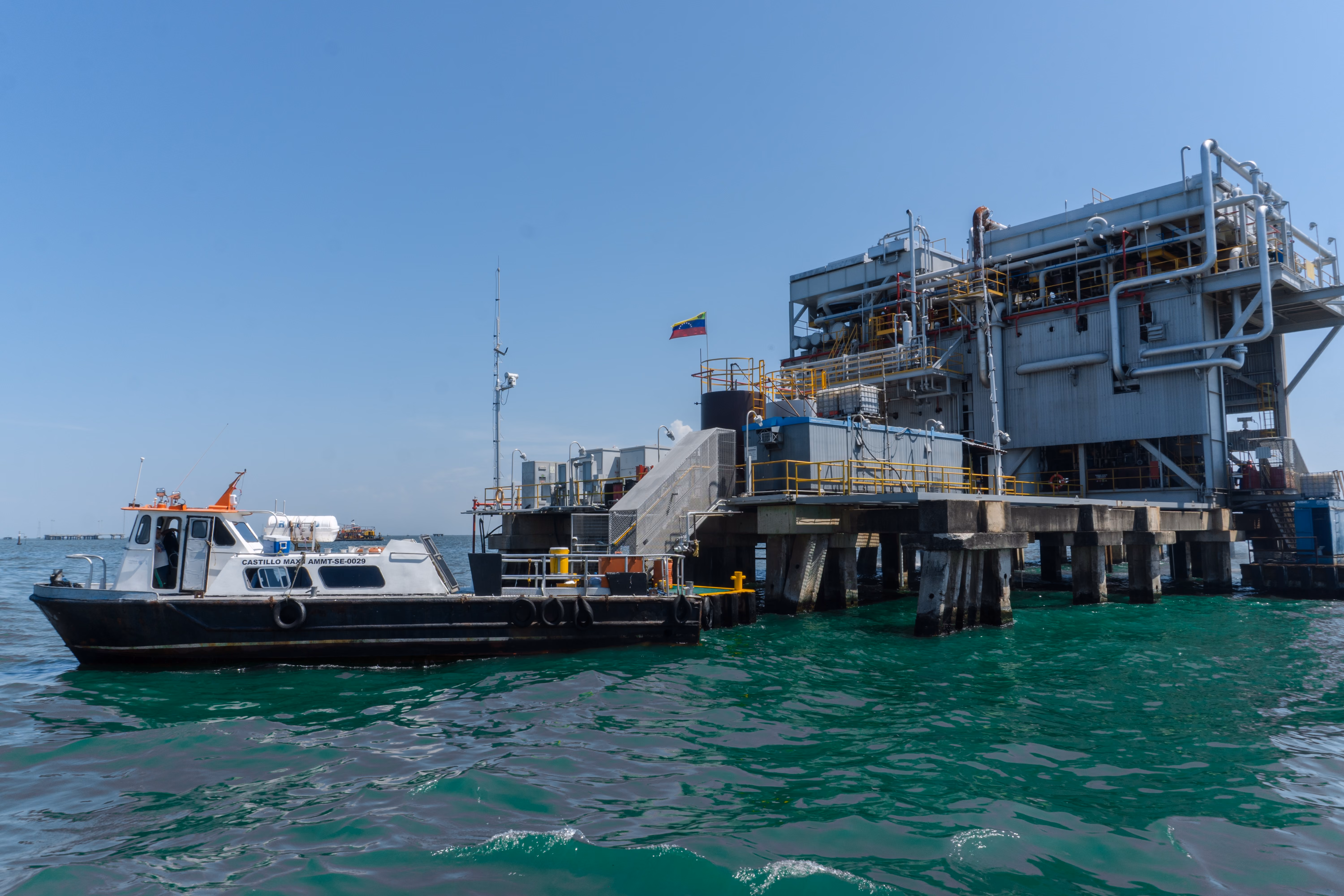 Crew boat alongside an offshore oil production platform flying the Venezuelan flag