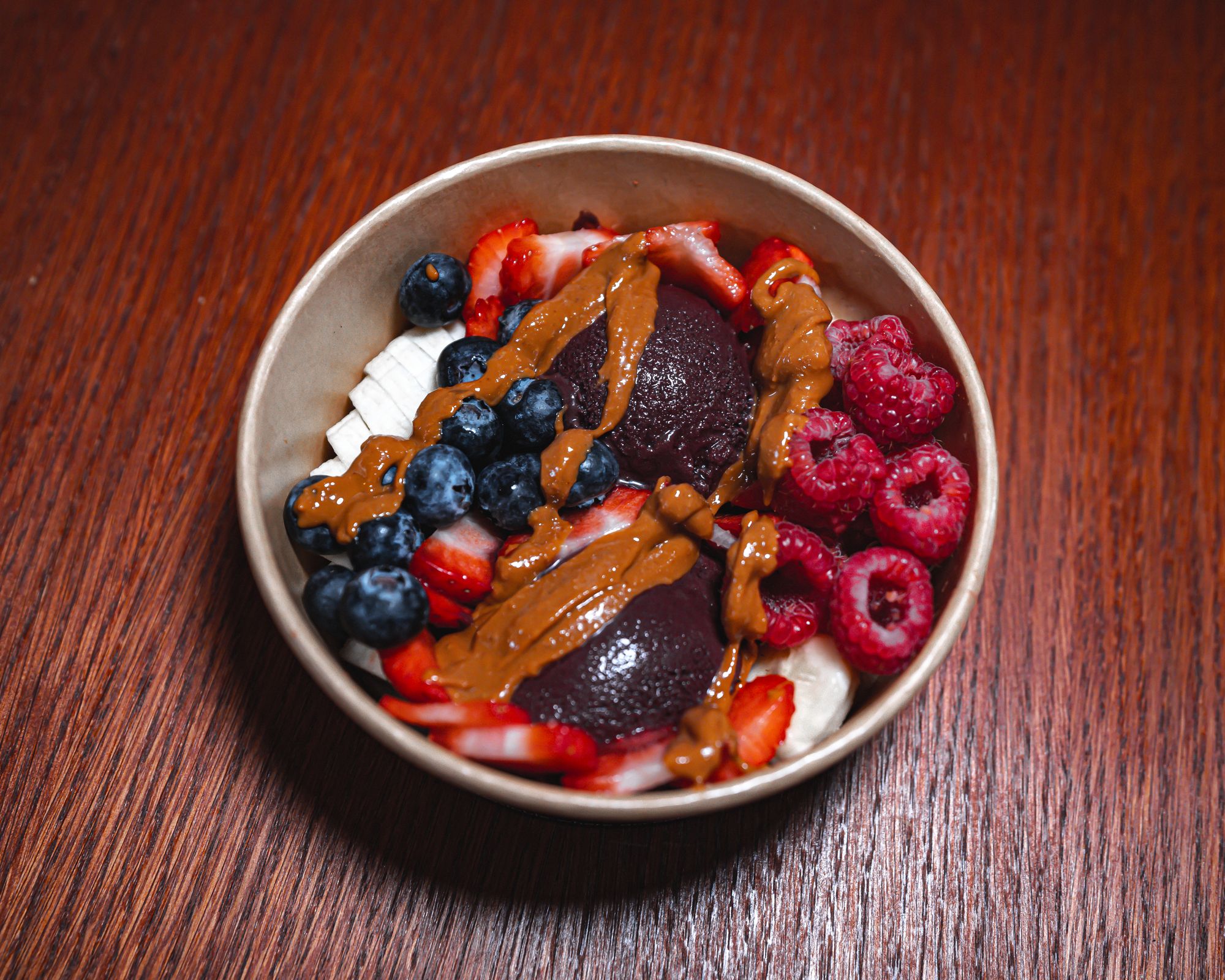 Overhead view of an organic acai bowl with banana, strawberries, blueberries, raspberries and nut butter in London