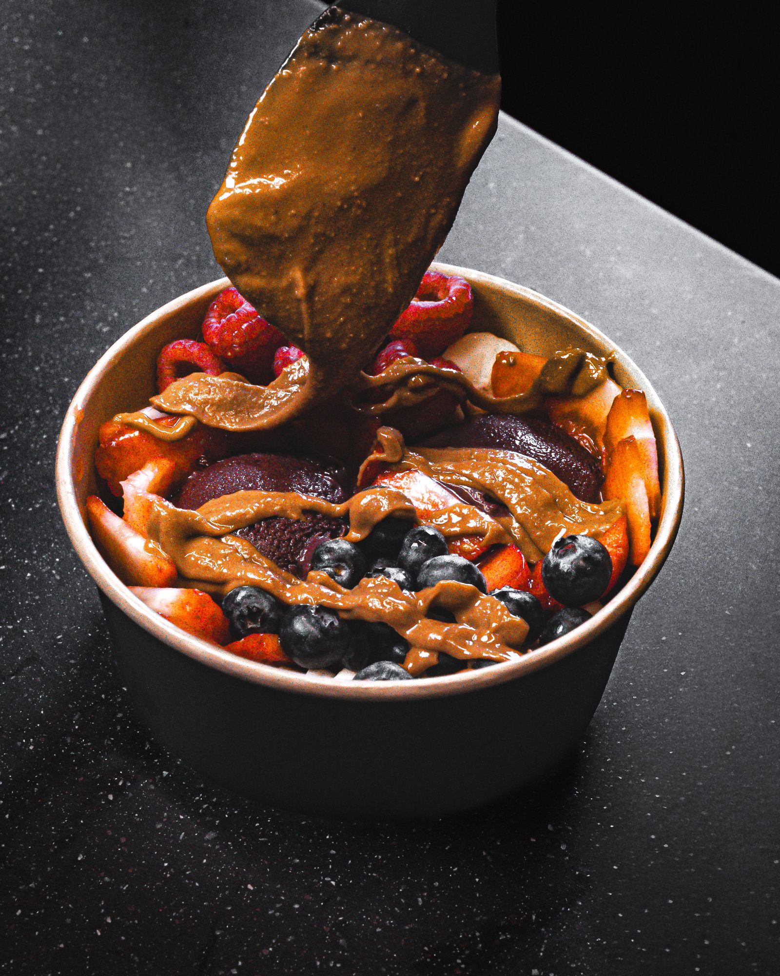 Almond butter poured over an organic acai bowl with strawberries, raspberries and blueberries at Ritual Cafe, Angel, London