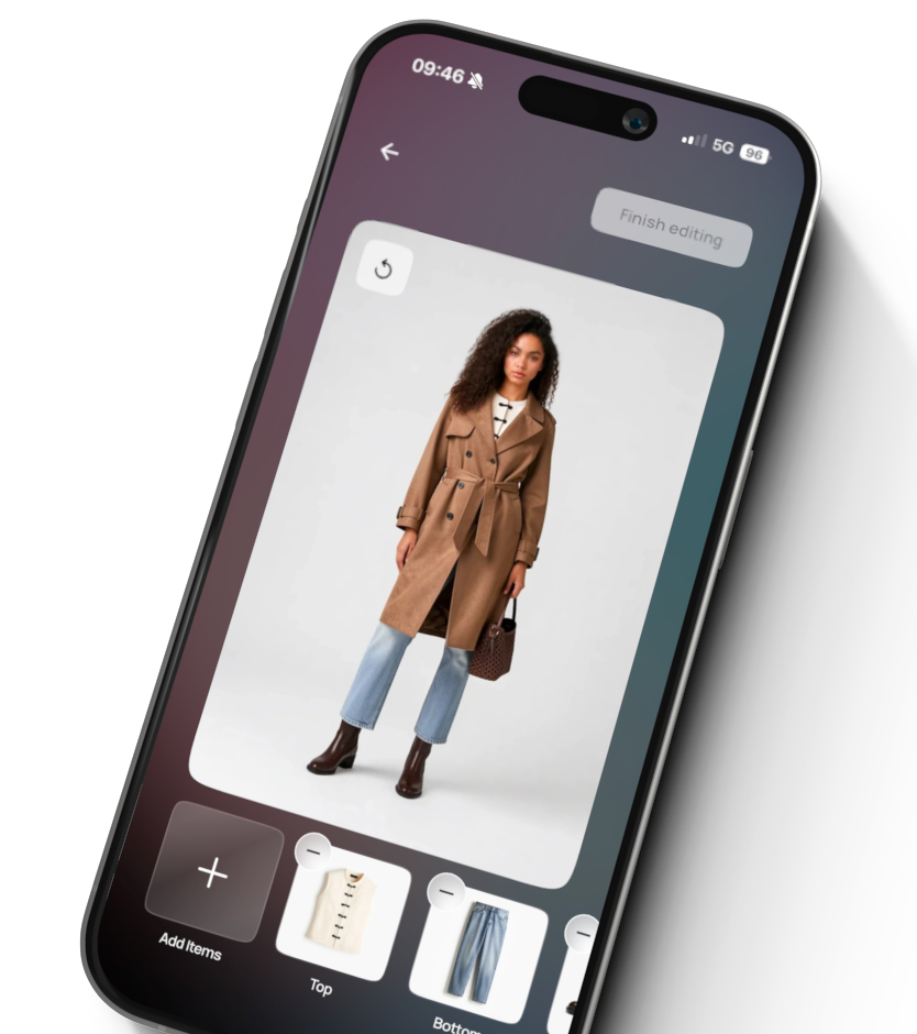 Smartphone screen showing a fashion app with a model wearing a brown belted trench coat, light blue jeans, dark brown ankle boots, and holding a brown handbag against a plain background. The app interface has options to add items and shows thumbnails labeled Top and Bottom.