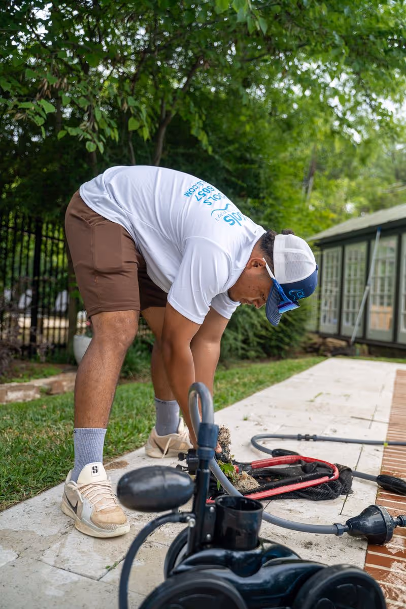 Residential pool maintenance service technician inspecting swimming pool