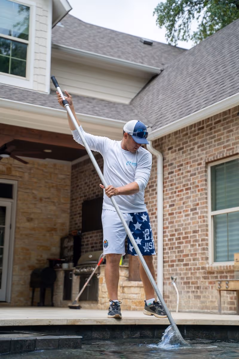 CK Pools technician cleaning a residential swimming pool in Houston, TX