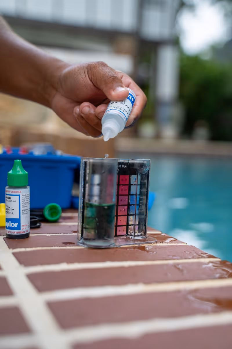 Pool technician testing and balancing residential swimming pool water