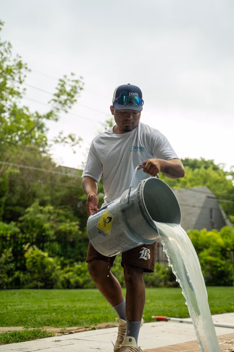 Pool technician adding treatment to a residential swimming pool