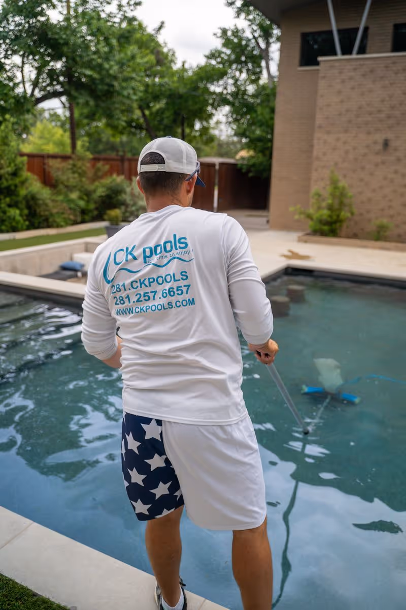CK Pools technician performing routine maintenance on a residential pool
