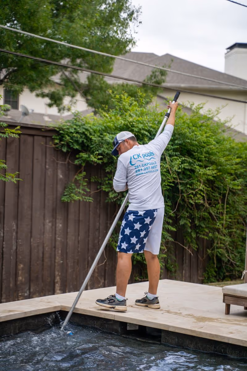 CK Pools technician brushing a residential swimming pool wall