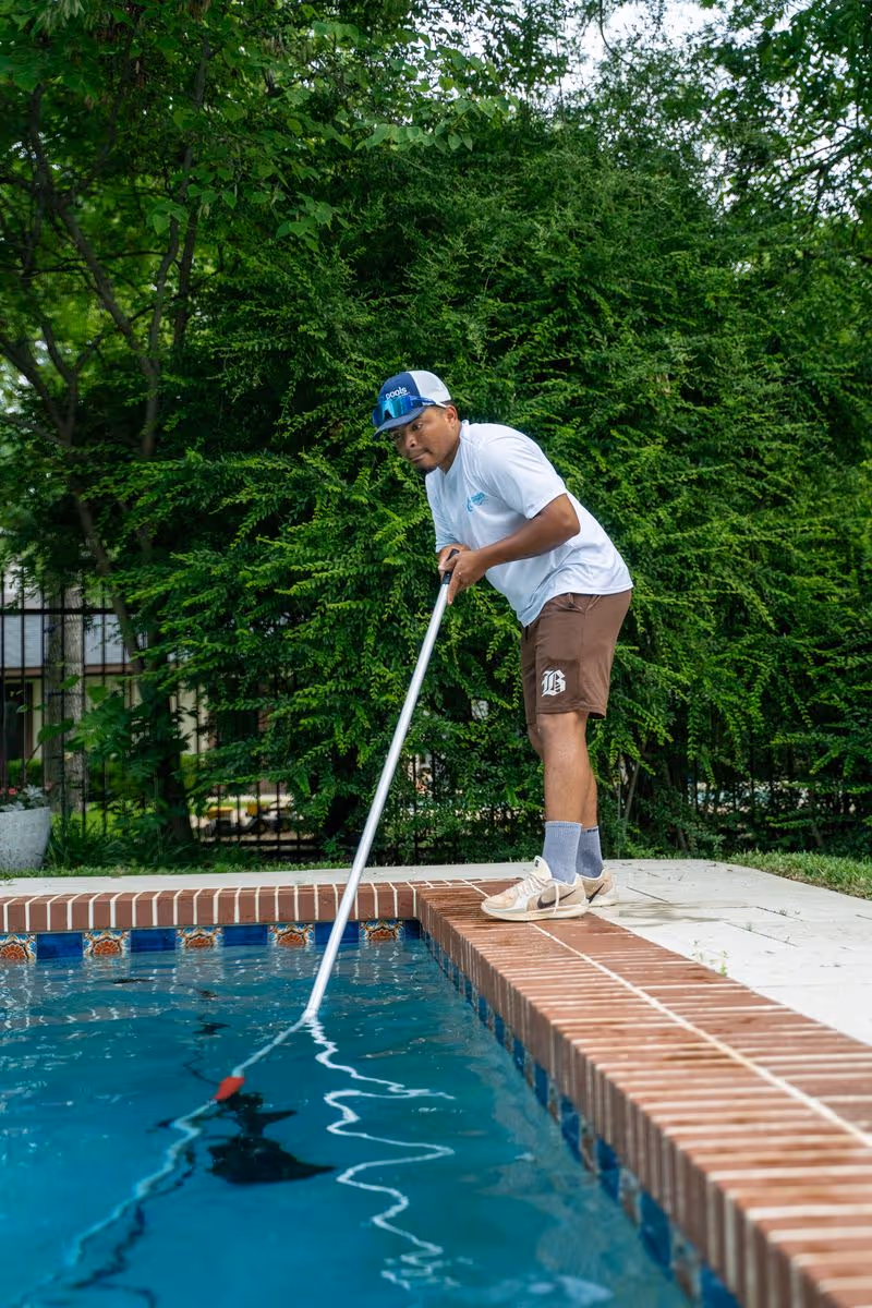 CK Pools technician brushing the sides of a residential swimming pool