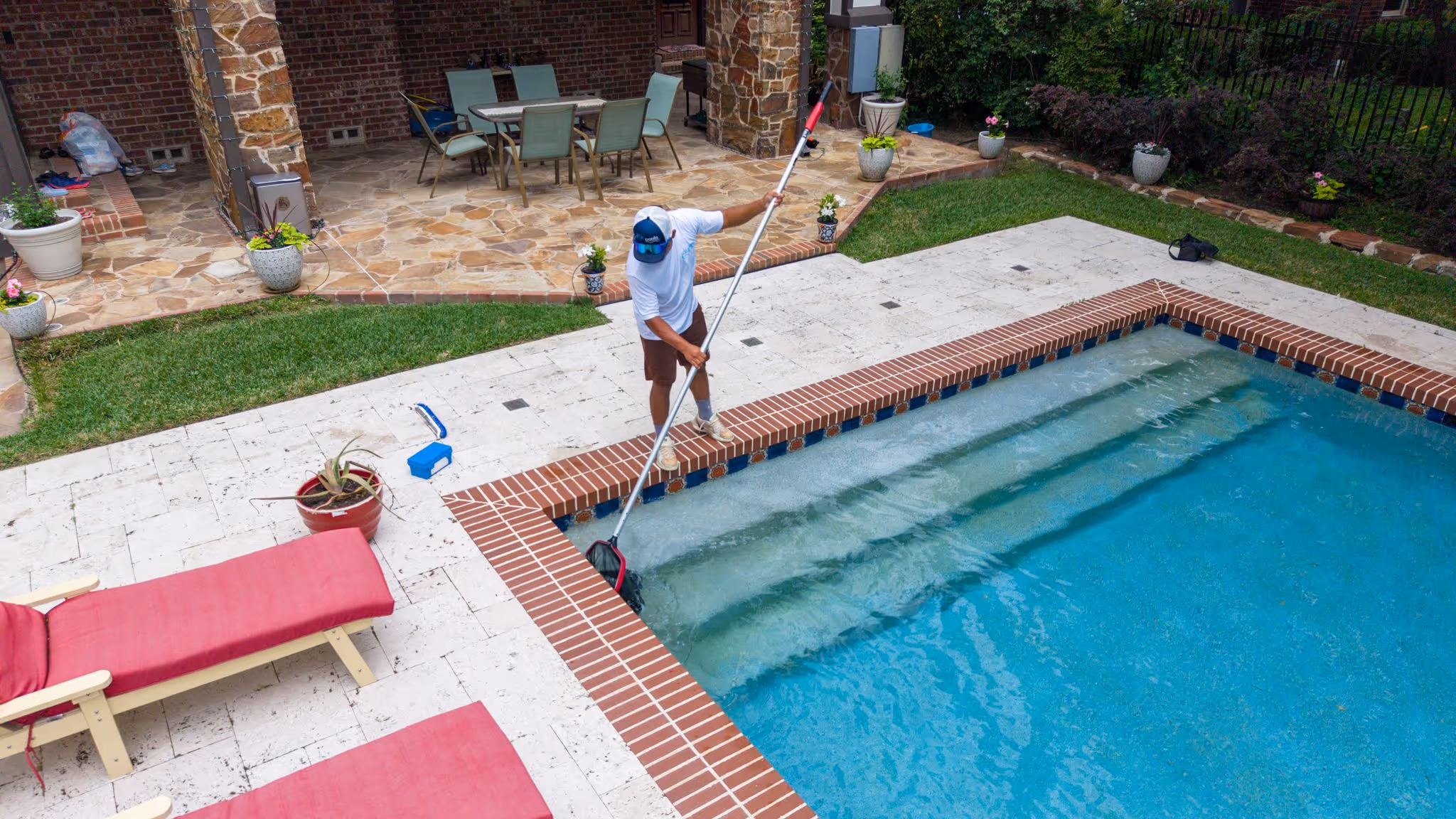 CK Pools technician skimming debris from a residential swimming pool