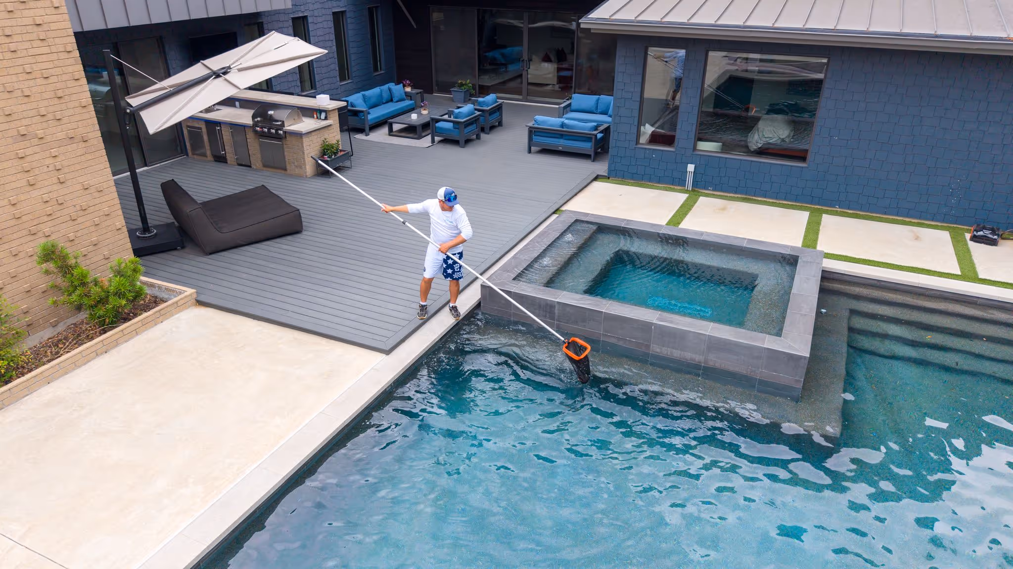 CK Pools technician skimming a modern backyard swimming pool