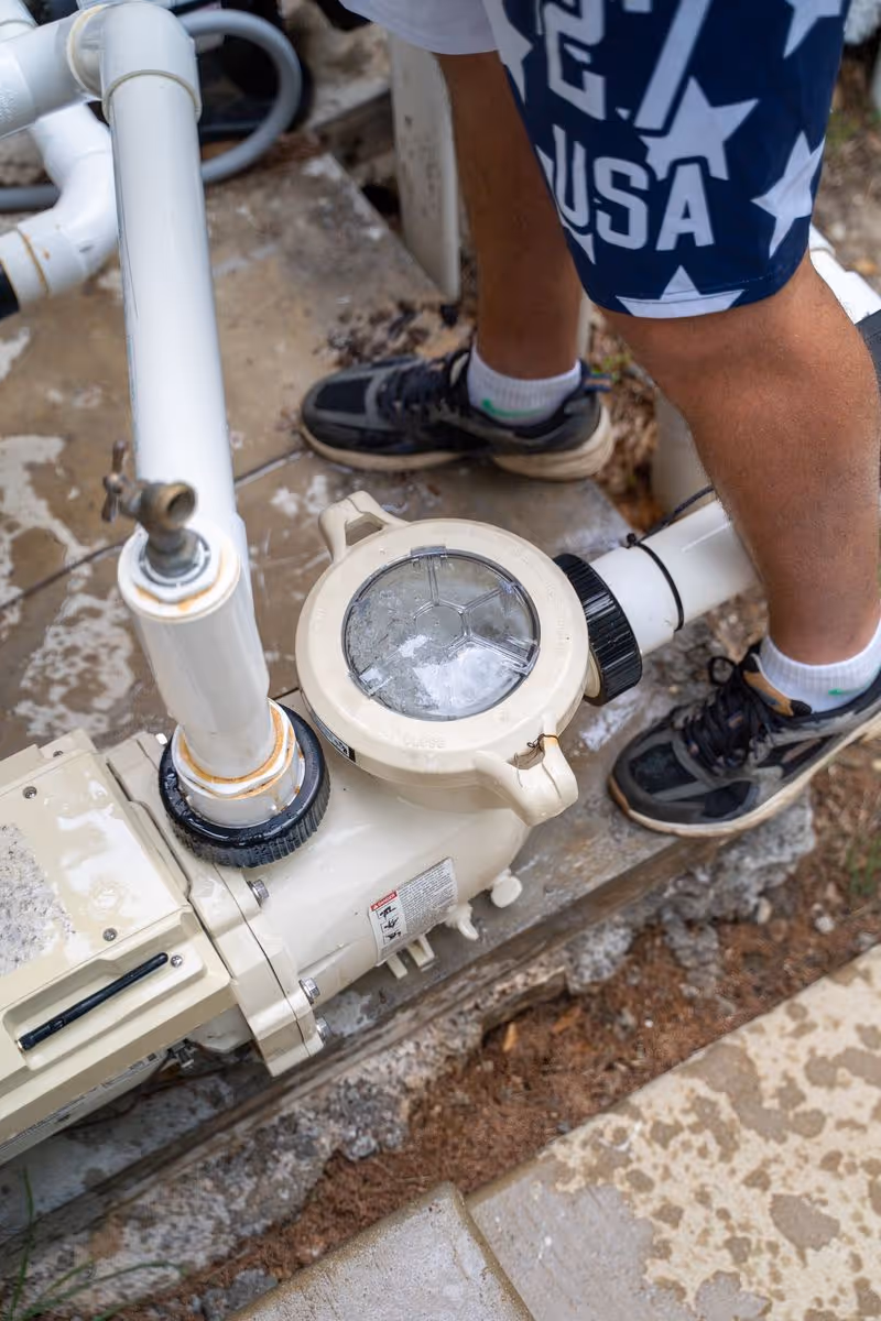Pool technician inspecting a residential pool pump and filtration system