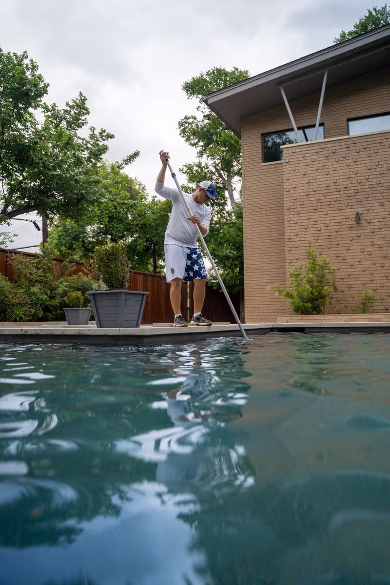 CK Pools technician cleaning a modern residential swimming pool