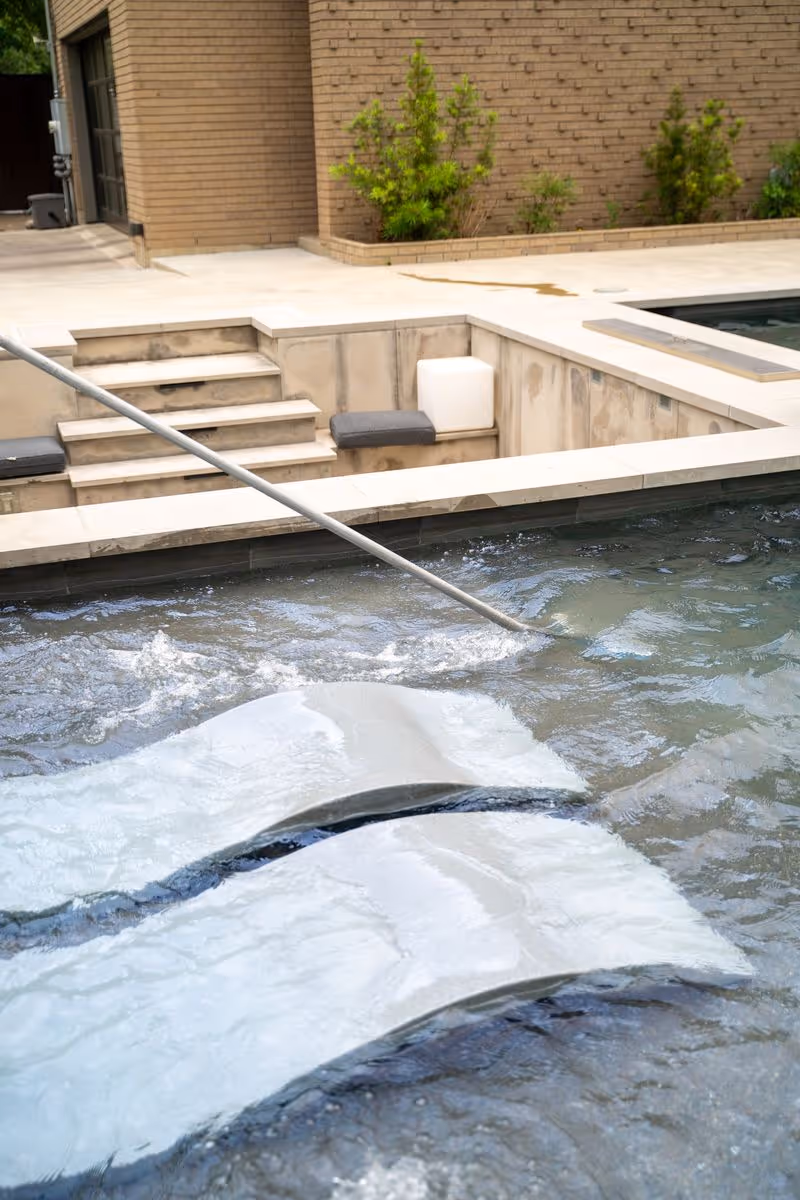 Swimming pool being professionally vacuumed during routine maintenance