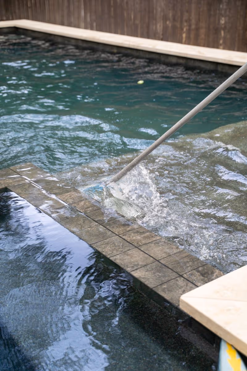 Professional pool vacuum cleaning the steps of a residential swimming pool