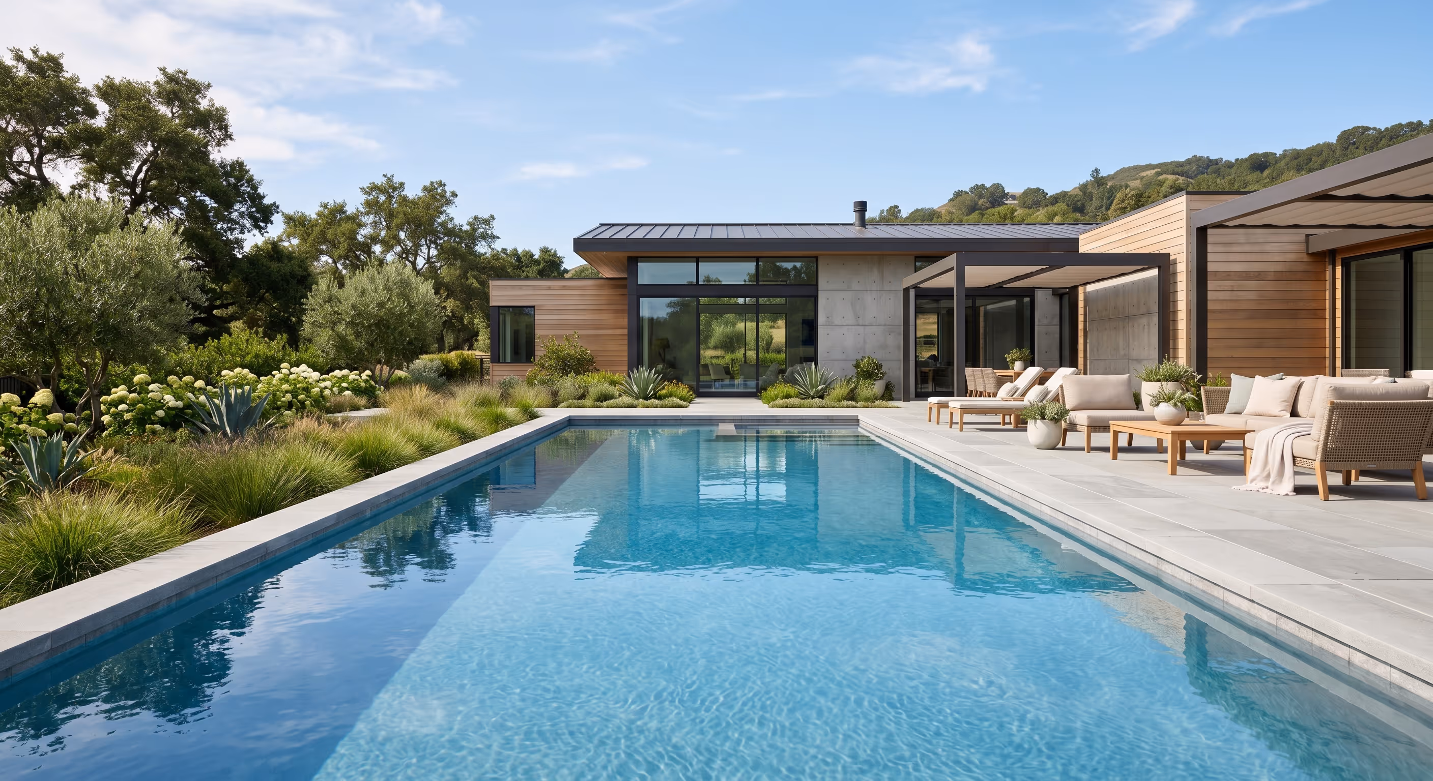 Modern residential swimming pool surrounded by landscaped gardens and an outdoor patio