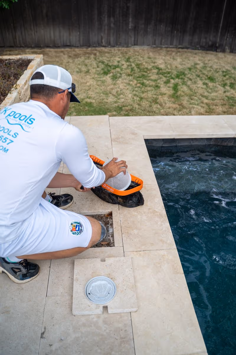 CK Pools technician cleaning the edge of a residential swimming pool