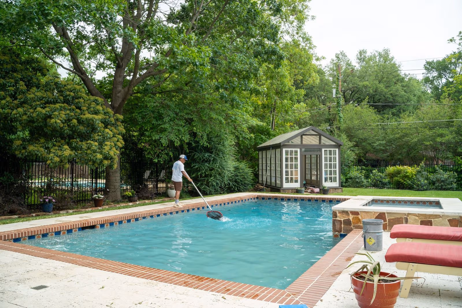 Technician performing routine maintenance on a large residential swimming pool