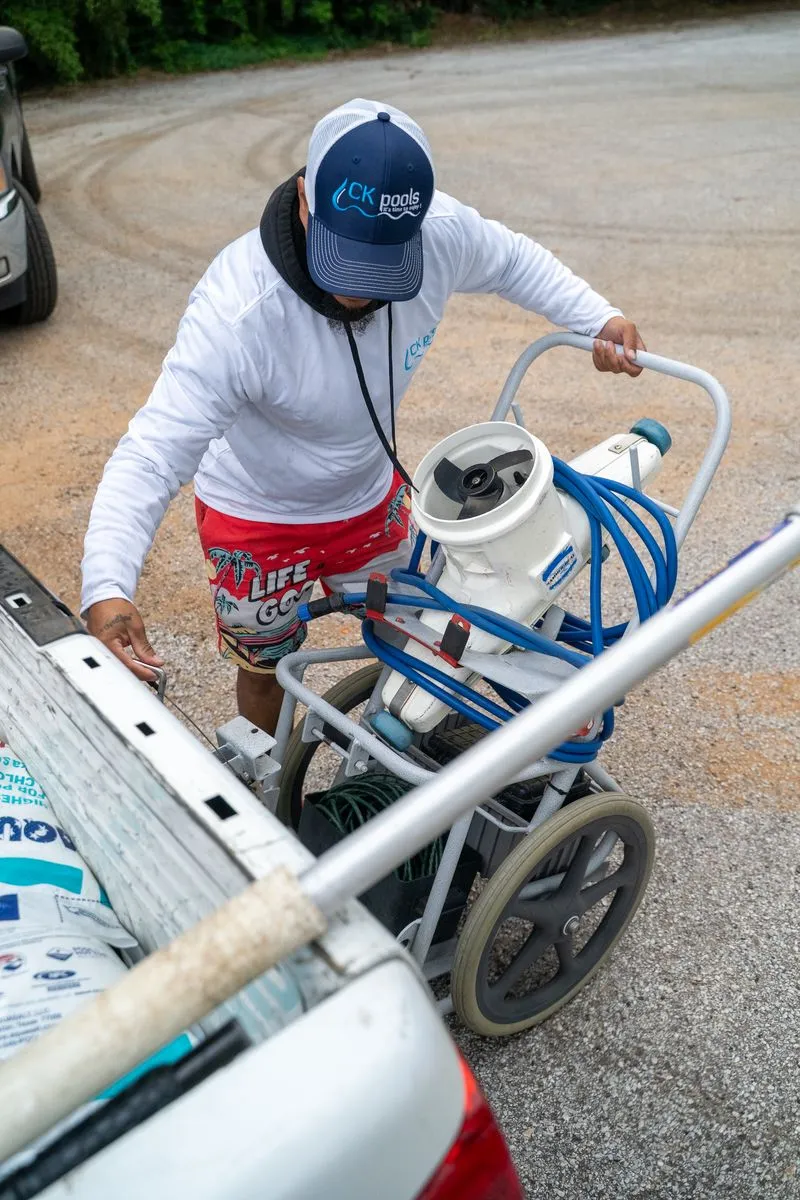 CK Pools technician unloading pool cleaning equipment from a service truck