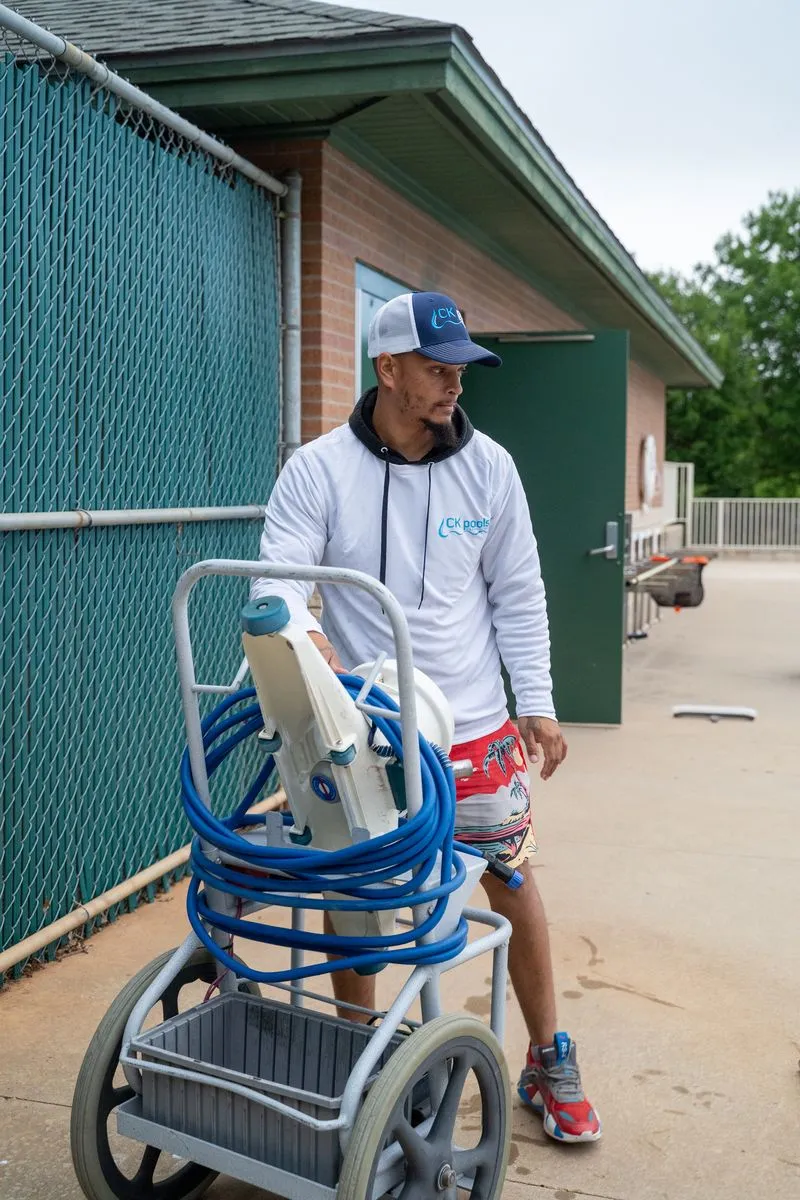 CK Pools technician transporting professional pool cleaning equipment