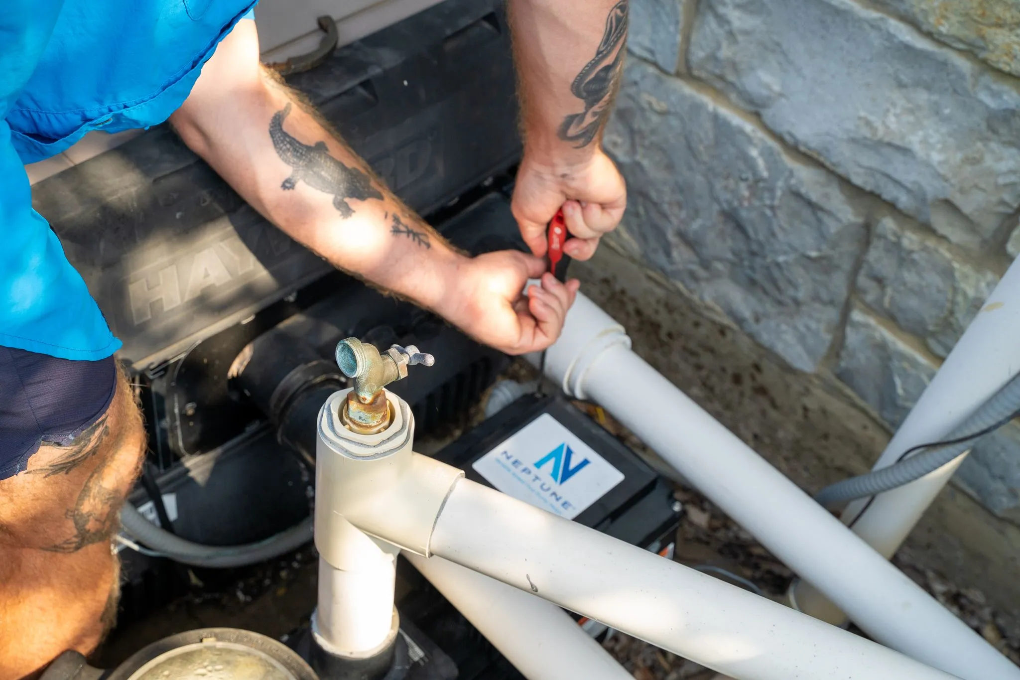 Pool repair technician tightening a connection on filtration equipment