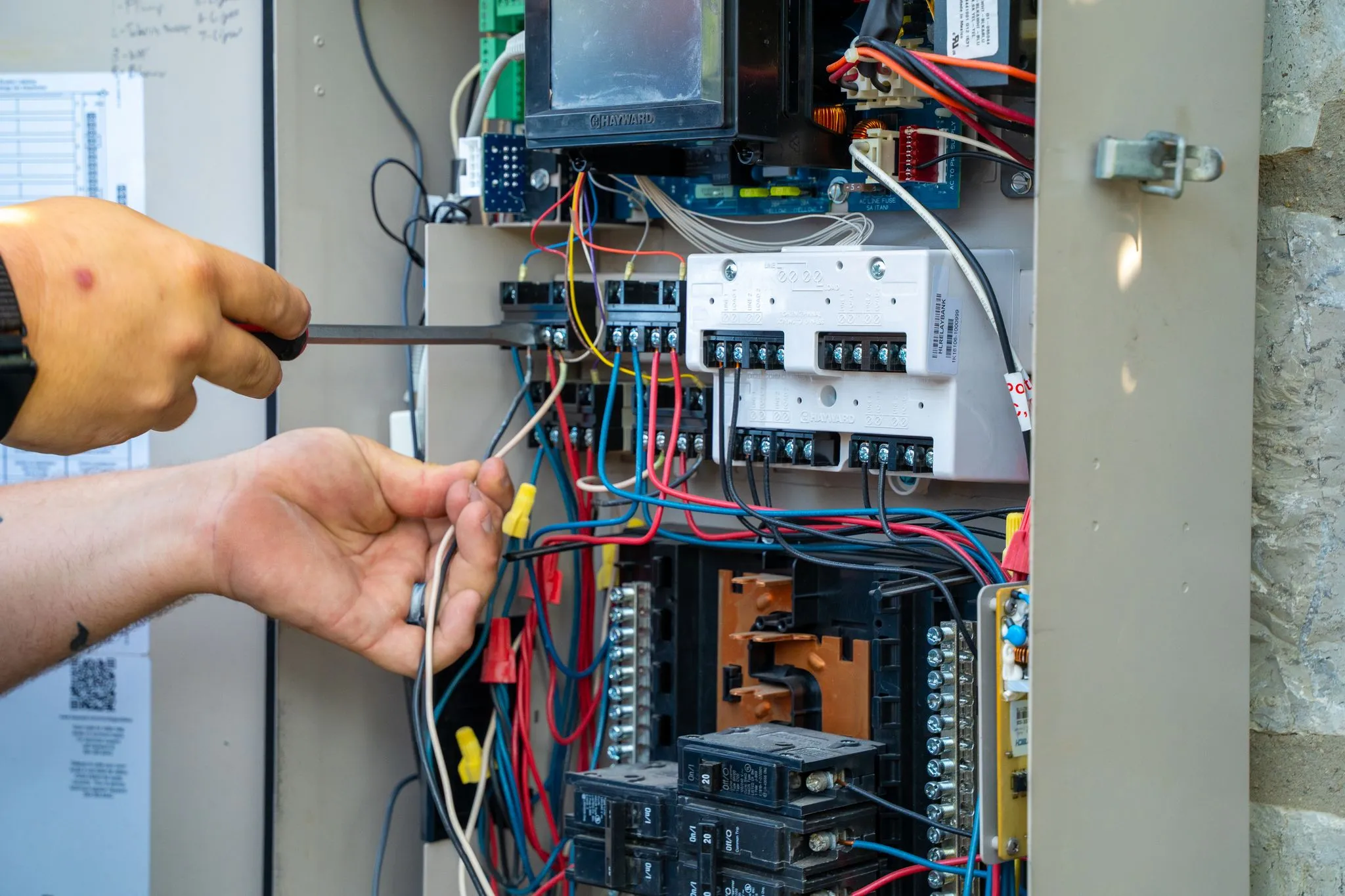 Pool repair technicians inspecting wiring inside an electrical control panel