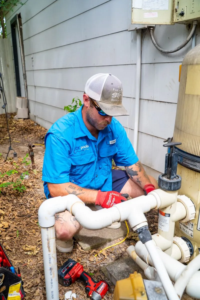 CK Pools technician repairing pool filtration pipes