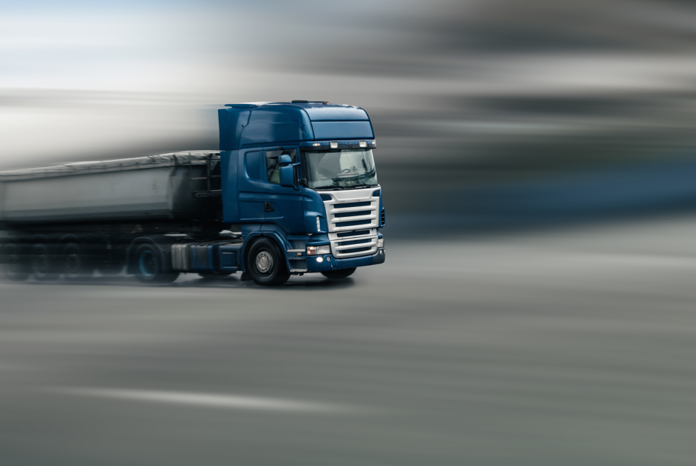 Blue bulk truck in motion against a blurred background